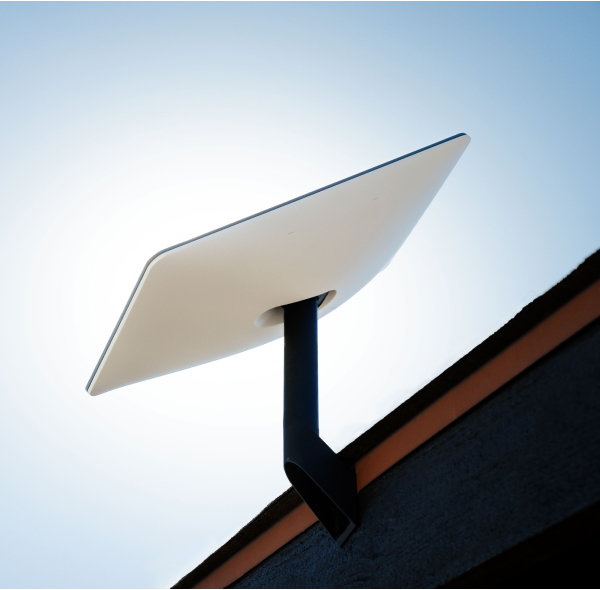 Image of a Starlink Satellite on a roof facing the sky with a white glow around it 