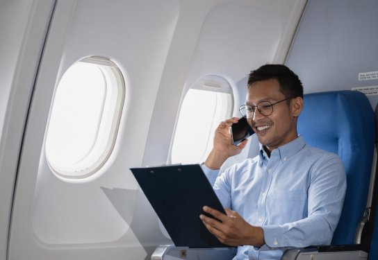 Man on a plan on the phone holding a clipboard