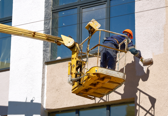 Photo of a worker painting the outside of the building