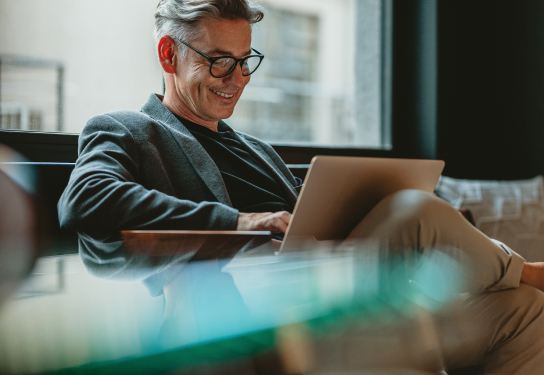 Image of a man sitting on a sofa on his laptop