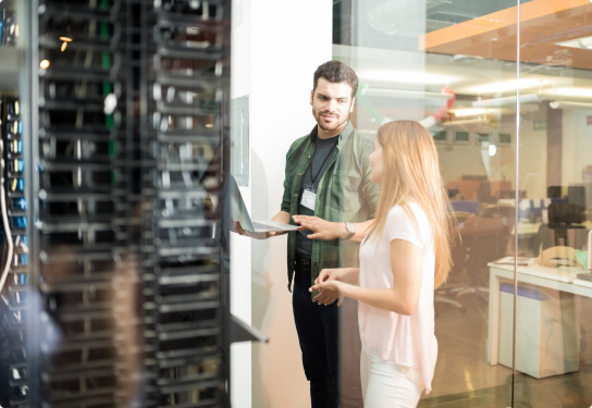 Photo of a man on his laptop and a woman in a server room