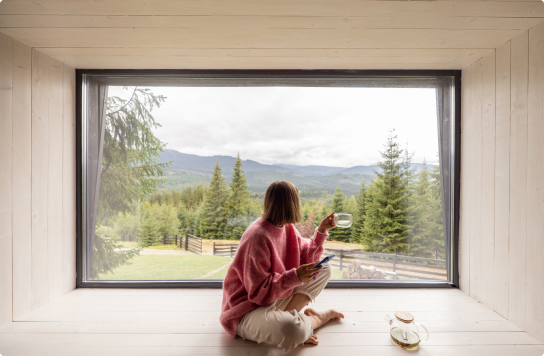 Image of a woman sitting and looking out a window with a cup of tea