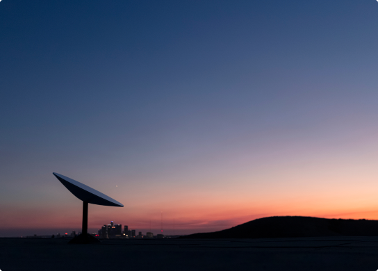 Image of a satellite with a sunset and a city skyline in the background