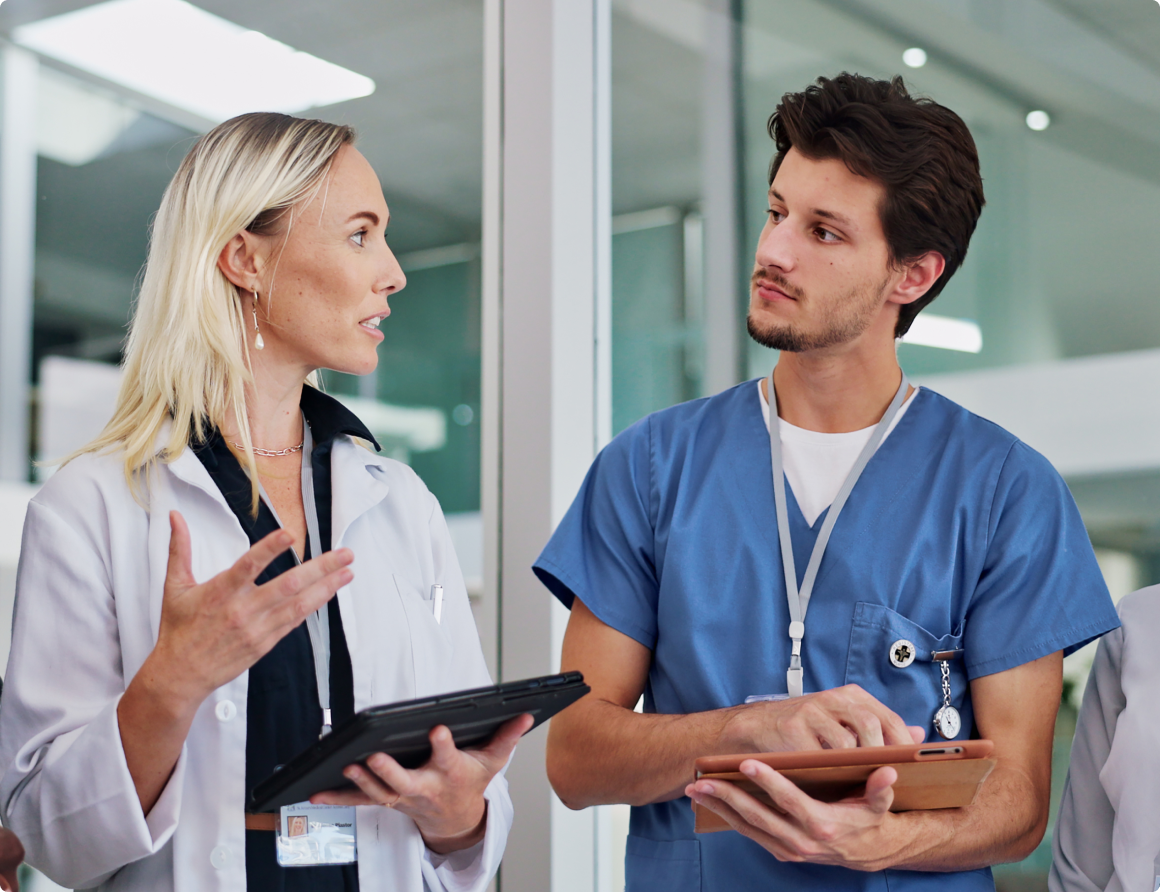 Image of a doctor and a nurse talking while holding tablets