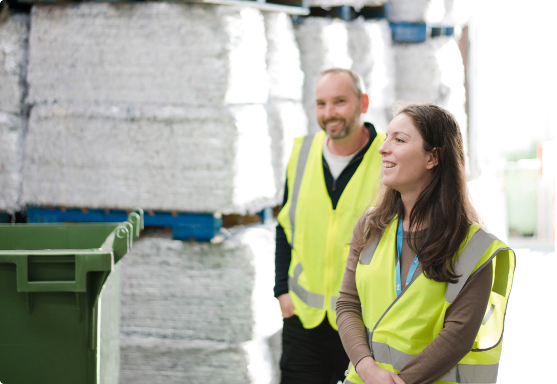 Photo of a man and a woman walking through workhouse wearing safety vests