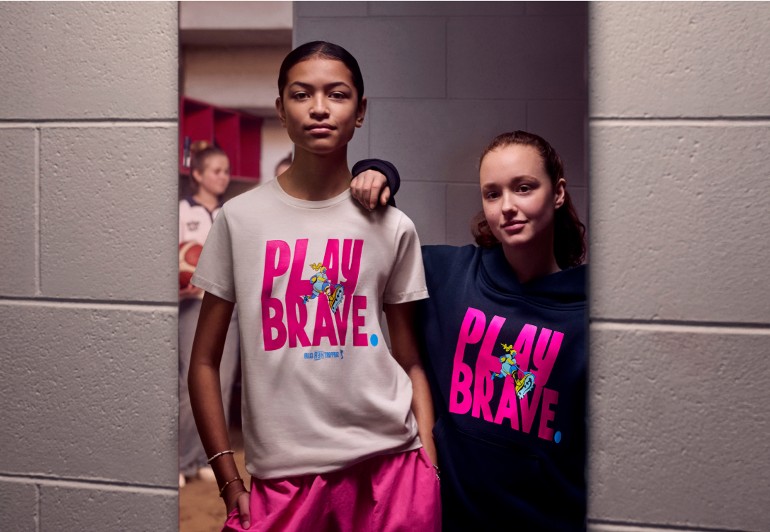 Photo of two girls looking in the mirror wearing the SupportHER merch