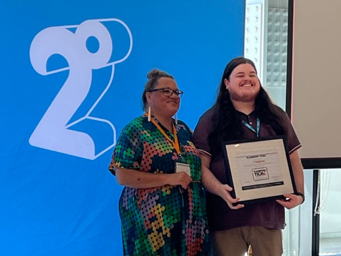 two people in front of the 2degrees logo, celebrating achieving the rainbow tick accreditation